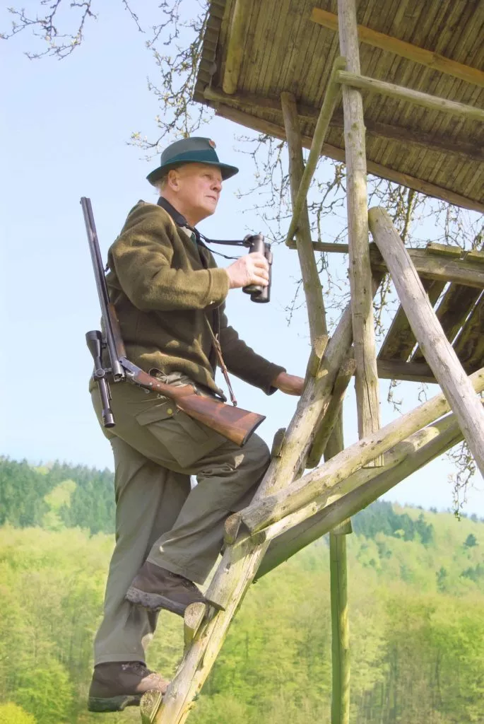 Abbildung: Jäger baumt von einem Hochsitz ab.