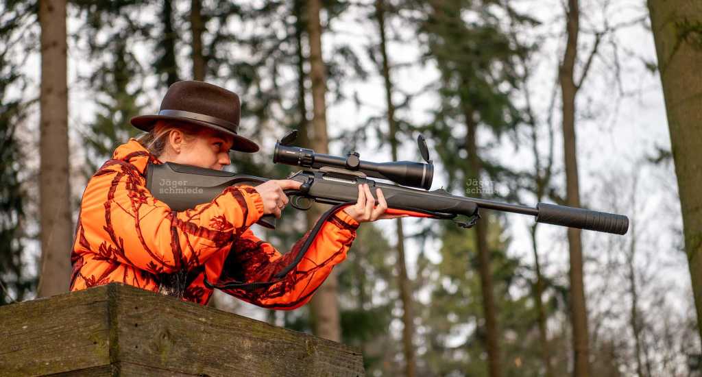 Abbildung: Jägerin bei einer Drückjagd mit der Büchse im Anschlag.